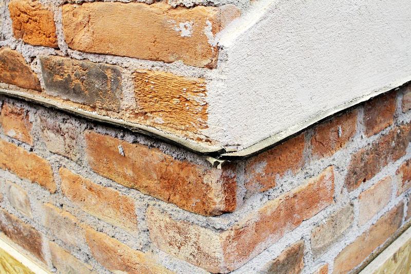 Een bakstenen muur met een zwarte vochtwerende folie tussen twee lagen stenen