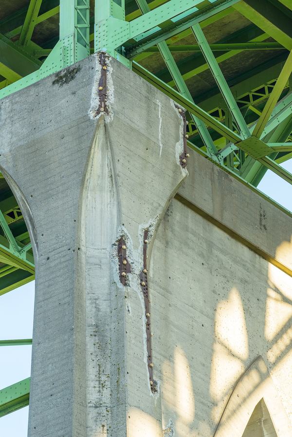 Een betonnen brugpijler met afgesprongen beton langs de hoek